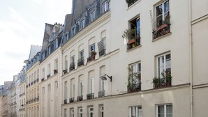 A row of classic European-style buildings with uniform facades, multiple windows, and balconies with potted plants.