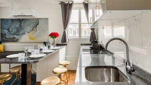 Une cuisine moderne dotée d’un plan de travail en marbre, d’un évier en acier inoxydable et de tabourets de bar.