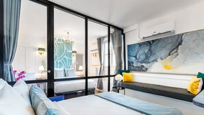 Une chambre d’hôtel avec un grand lit, une vue à travers une porte vitrée et une œuvre d’art moderne accrochée au mur.