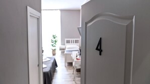 A hallway with a door marked '4' leading to a room with a bed and a bedside table. - Bed and Best Triple/Quadruple deluxe (Roma)