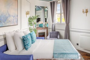 A bedroom with a bed, a chair, a mirror, and a window with curtains. - Merveil Luxury Suite Royale II - Saint Honore view (Paris)
