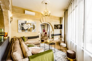 Un salon moderne avec un canapé, un lustre et une grande fenêtre.