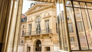 A historic building with ornate architecture, large windows, and a balcony with wrought iron railings. - Merveil Signature Suite - Valois - Louvre view (Paris)