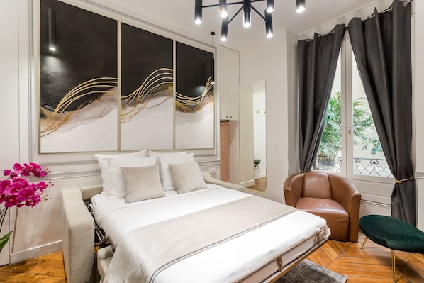 Relax in a spacious room with a large bed, abstract artwork, and a cozy seating area.