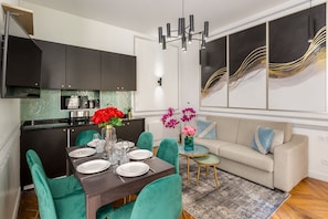Enjoy meals and relaxation in this stylish dining and living area, featuring a dining table, comfortable seating, and a large abstract art piece.