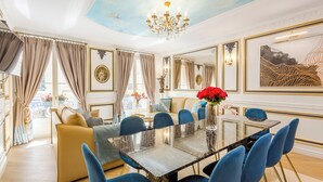 Ein luxuriöser Speisesaal mit einem Marmortisch, blau gepolsterten Stühlen und einer Chandelüster.