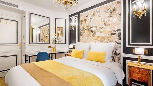 Una habitación de hotel con una cama grande, un escritorio y un espejo.