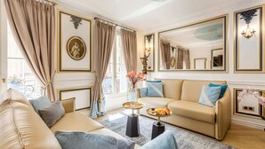 Ein luxuriöses Wohnzimmer mit einem beigefarbenen Sofa, einem Couchtisch mit Gebäck und einem großen Spiegel.