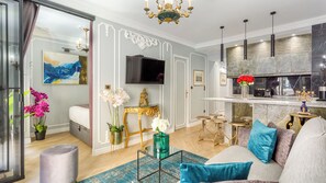 A modern living room with a sofa, a coffee table, and a TV. There is a bar area with stools and a decorative vase. - Merveil - Luxury Suite -Champs Elysees-Ponthieu II (Paris)