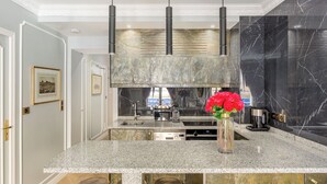 Una cocina moderna con encimeras de granito, campana extractora de acero inoxidable y un florero con flores rojas en la isla.