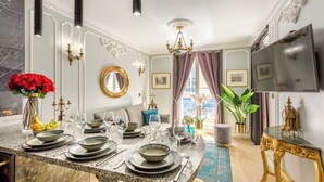 Comedor con encimera de mármol, mesa puesta y un amplio ventanal con cortinas.