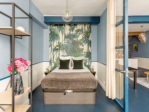 Une chambre moderne avec un grand lit, une armoire et un espace bureau.