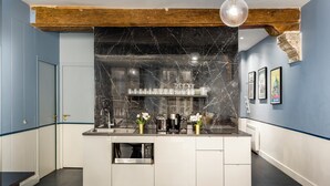 Una cocina moderna con salpicadero de mármol, electrodomésticos de acero inoxidable y una viga de techo de madera.