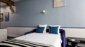 A hotel room with a bed, a nightstand, a lamp, and artwork on the wall.