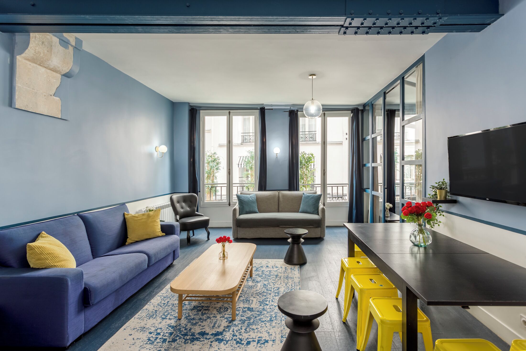 Un salon moderne avec un canapé, une table basse et des tabourets jaunes.