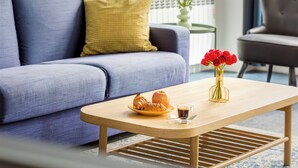 Una sala de estar moderna con un sofá, una mesa de centro, un jarrón con flores y una silla.