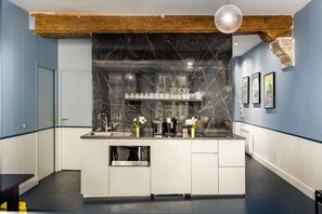 Een moderne keuken met een marmeren achterwand, roestvrijstalen apparatuur en een houten balk.