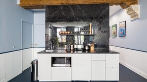 A kitchen with a black marble backsplash, stainless steel appliances, and a trash can.
