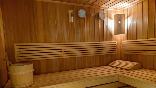 Eine Holzsauna mit Bänken und einem Holzeimer.