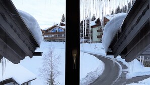 A snowy landscape with buildings and icicles hanging from the roof. - R.M.G. family ski to door apartments   Top 1 (Bach)