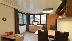 Eine moderne Küche mit Holdekor-Schränken, einem Esstisch und Stühlen. Ein Fenster bietet Blick auf ein Haus und Bäume.