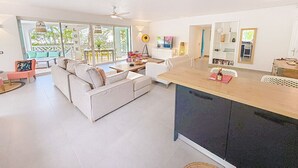 A spacious living area with a sofa, coffee table, and a dining area with a kitchen counter.