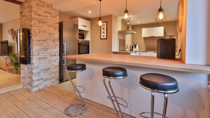 Une cuisine moderne avec un mur d’accent en pierre, un plancher en bois et des tabourets de bar.