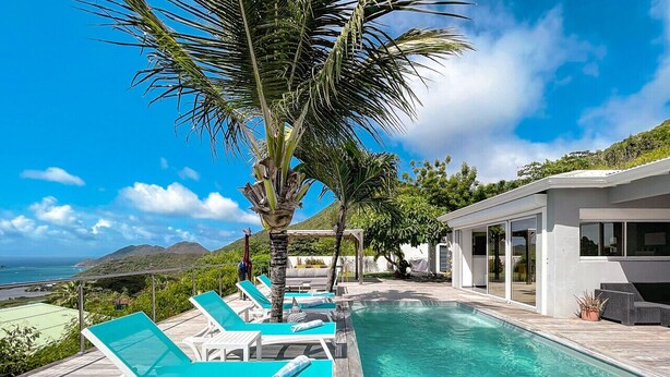 A poolside area with lounge chairs and a modern building.