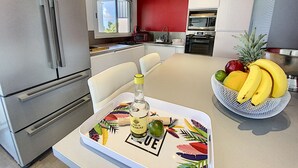 A modern kitchen with stainless steel appliances, a fruit bowl on the counter, and a bottle of liquor on a tray.