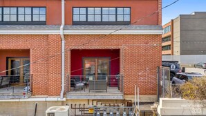 A two-story building with a red brick facade, a red door, and a small outdoor seating area with metal chairs. - Dickson St. Hideaway (Fayetteville)