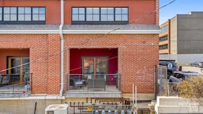 A two-story building with a red brick facade, a red door, and a small outdoor seating area with metal chairs. - Dickson St. Hideaway (Fayetteville)