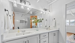 A modern bathroom with a large mirror, two sinks, and a potted plant. - Dickson St. Hideaway (Fayetteville)