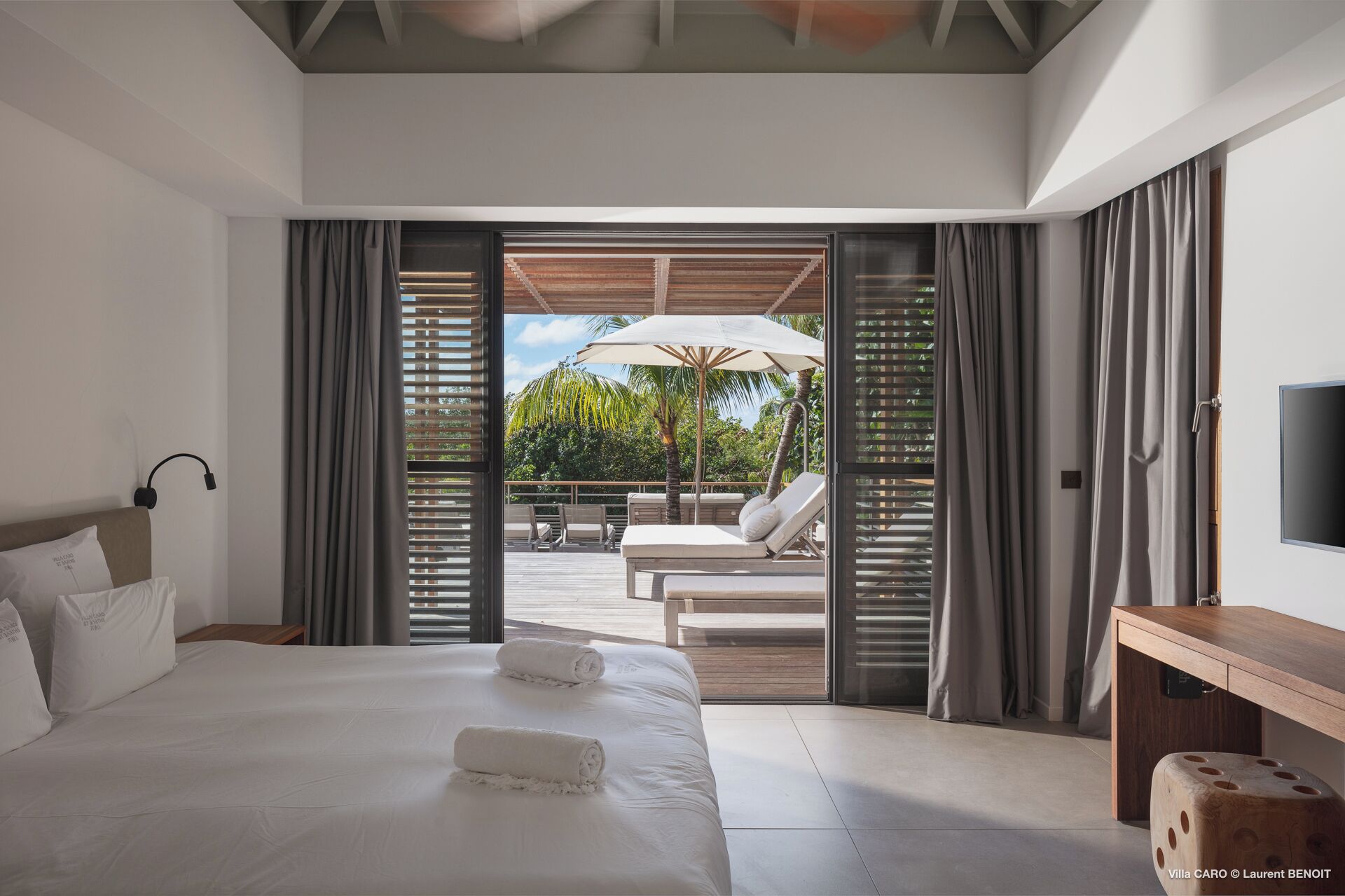 Une chambre moderne avec un grand lit, un bureau et une vue sur un espace extérieur aménagé avec une table et des chaises.