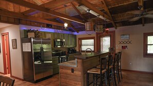Una cocina con una isla central, taburetes de bar y un refrigerador de acero inoxidable.