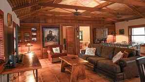 Un amplio salón con muebles de madera, una mesa de comedor y una cocina al fondo.