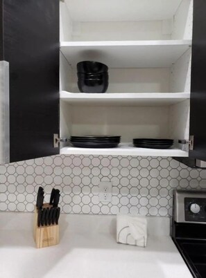 A kitchen with white countertops, a hexagonal tile backsplash, and a black appliance.