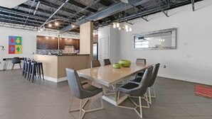 Une cuisine moderne dotée d’un îlot central, d’un coin repas avec une grande table et des chaises, et d’un comptoir de cuisine avec des tabourets.