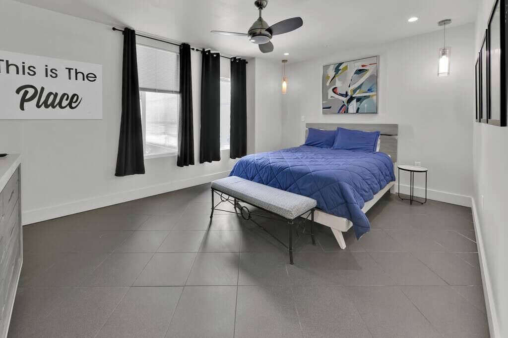 Une chambre à coucher moderne avec un lit, un banc et une œuvre d’art.