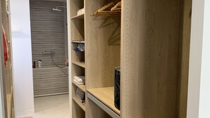 Un armario espacioso con repisas abiertas, espacio para colgar ropa y una puerta con espejo.