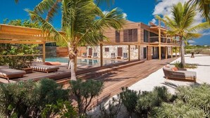 Ein modernes Resort mit Holzterrasse, Liegestühlen, Pool und Palmen.