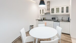 Eine moderne Küche mit weißen Schränken, einem runden weißen Tisch und vier weißen Stühlen.