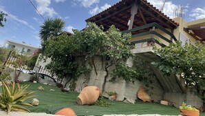 A building with a tiled roof, a stone wall, and a green roof garden. - Alonaki House (Listaros)
