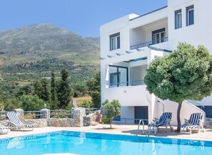 Un hôtel moderne doté d’une piscine, de chaises longues et offrant une vue sur les montagnes.