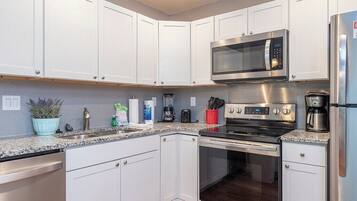 A modern kitchen with white cabinets, stainless steel appliances, and a granite countertop.