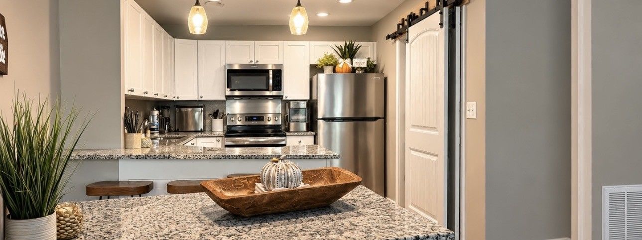 A modern kitchen with white cabinets, stainless steel appliances, and a granite countertop.