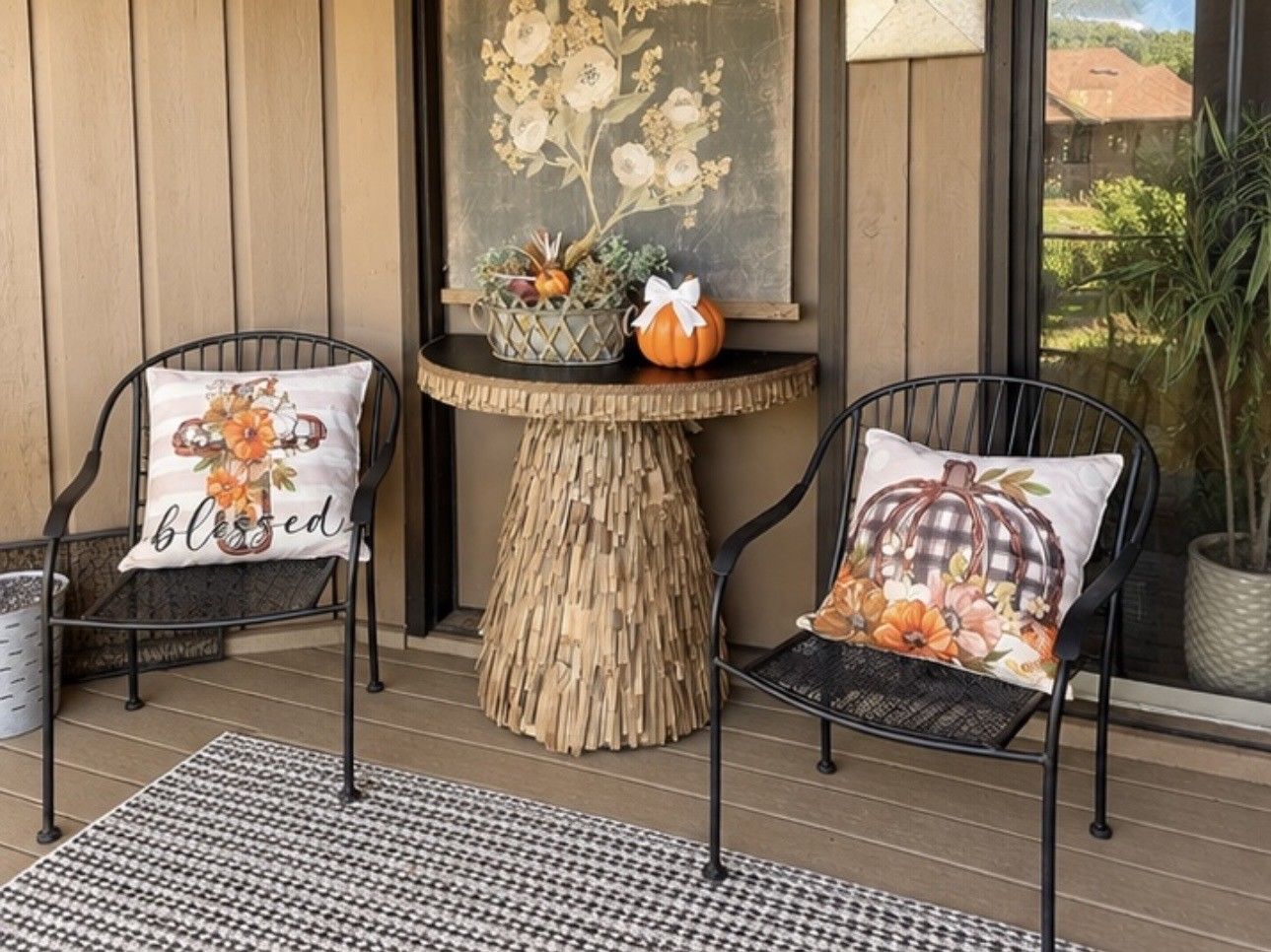 Two chairs with decorative pillows, a woven table centerpiece, and a view of the outdoors.