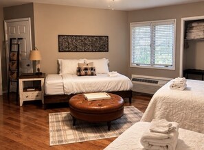 A bedroom with a bed, a nightstand, a lamp, a window with blinds, and a radiator. - Fairway Villa 1203 at Rumbling Bald (Lake Lure)