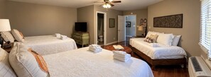 A hotel room with two beds, a television, a heater, and a door leading to a bathroom.