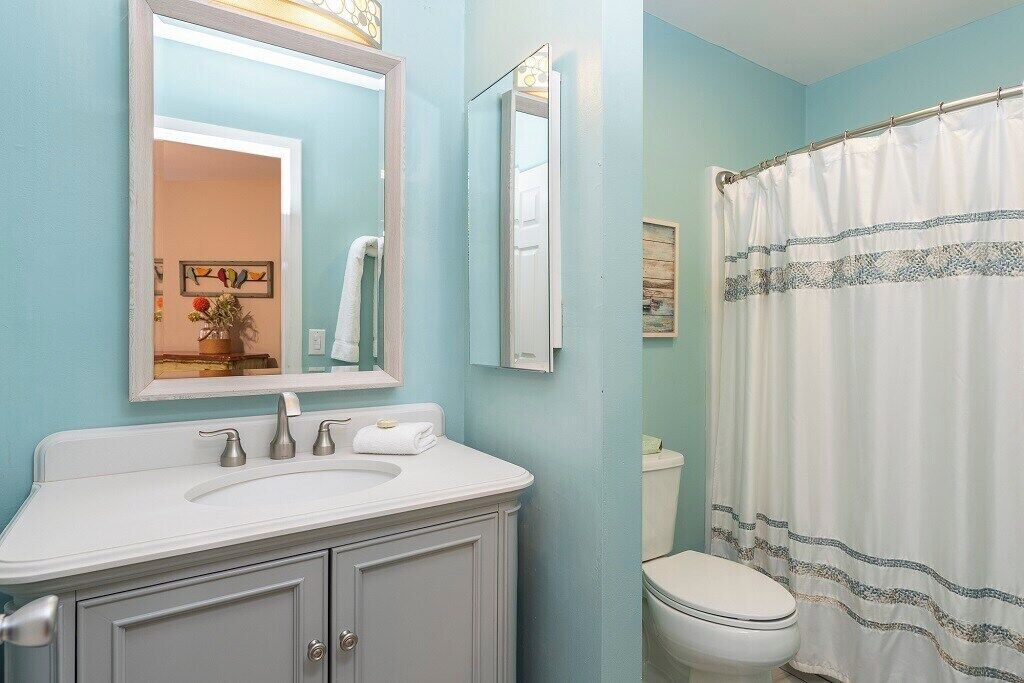 A bathroom with a white sink, a mirror, a toilet, and a shower curtain.