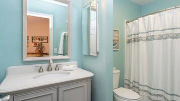 A bathroom with a white sink, a mirror, a toilet, and a shower curtain.